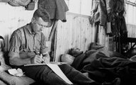 Hackney barátja, a belfasti John Ewing naplót ír vagy levelet családjának, miközben katonatársa alszik az ágyán, 1915-ban, az észak-írországi Randalstown Campben.